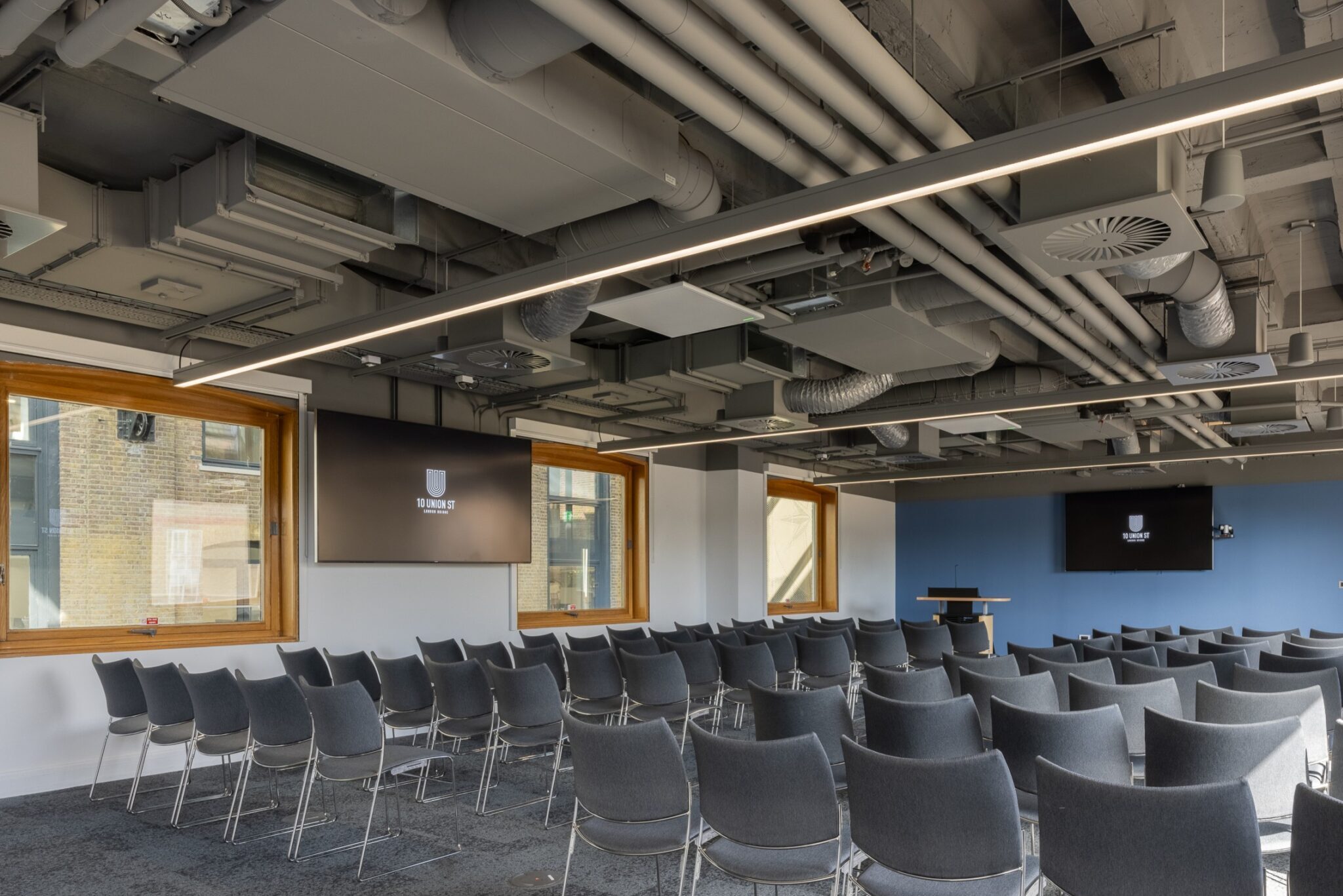 Flexible conference space at 10 Union Street with theatre-style seating, multiple presentation screens and abundant natural light, ideal for conferences, seminars, presentations and corporate events.
